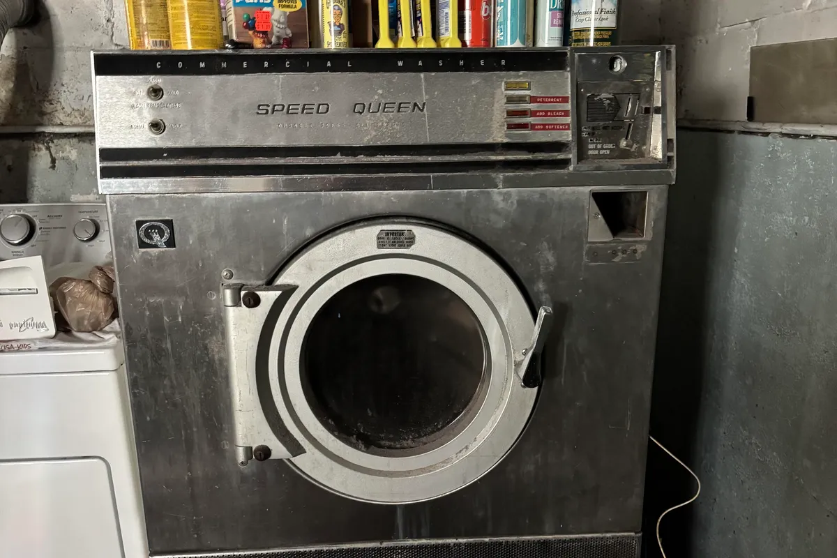 Vintage coin-operated Speed Queen commercial washer in a Norwood Park basement before removal