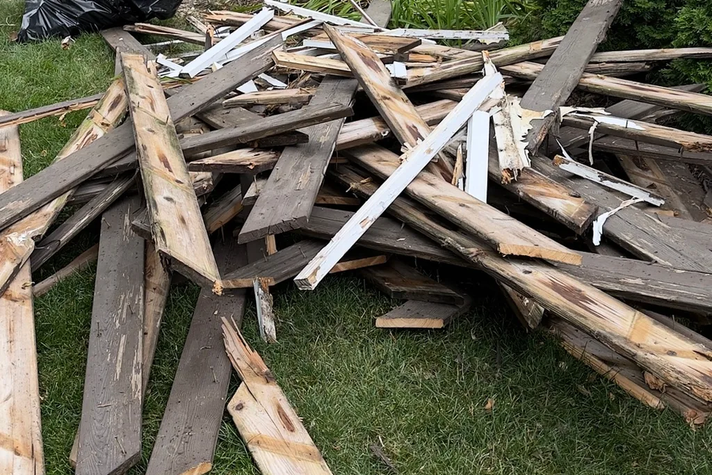 Close-up of broken wood boards and white trim pieces in a construction debris pile before junk removal in Wheaton
